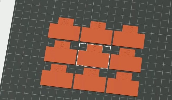 OrcaSlicer flow rate Pass 1 test print on the build plate showing nine orange blocks each labelled with a different flow modifier value