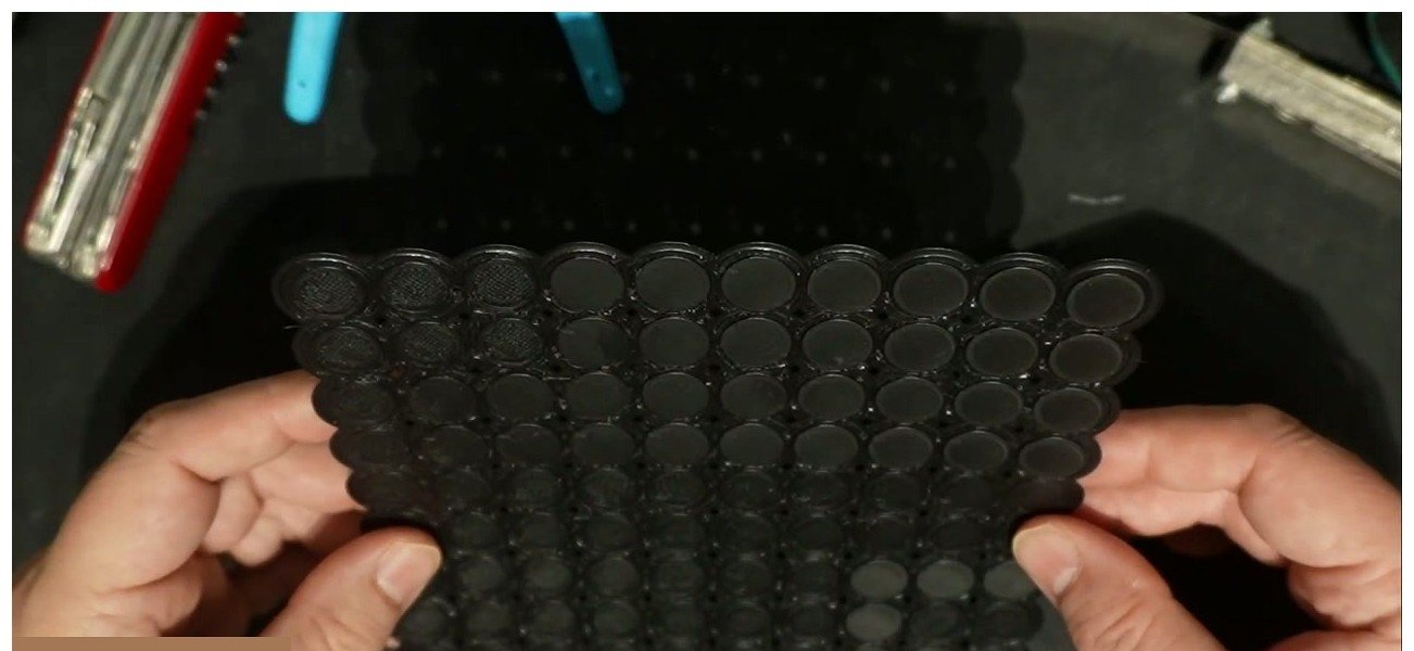 A 3D printed part held up showing a matrix of different ironing test settings on its top surface