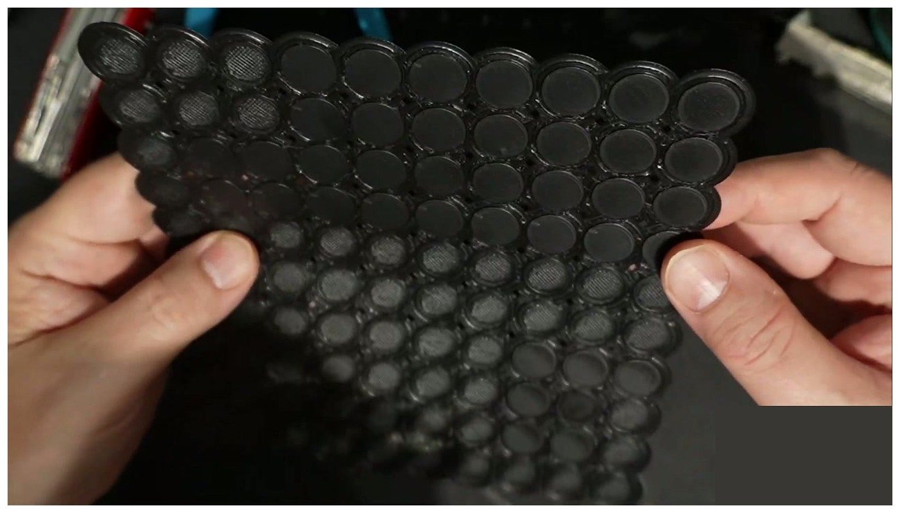 A 3D printed plaque held in hand showing the ironed top surface and the un-ironed bottom for comparison